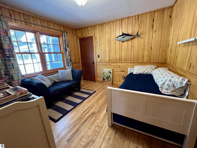 bedroom with light wood-style floors and wooden walls