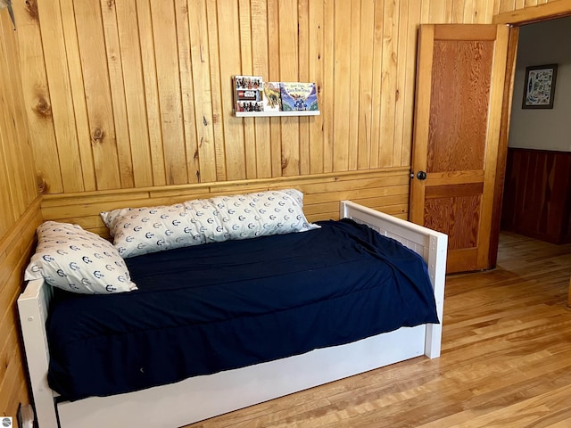 bedroom featuring wood finished floors and wood walls