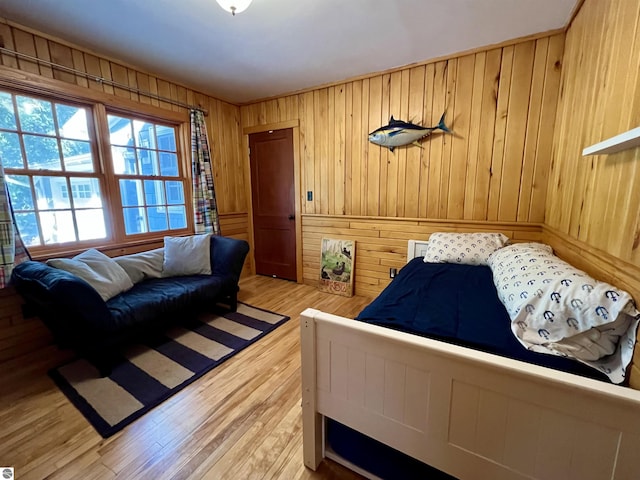 bedroom with light wood-type flooring and wooden walls
