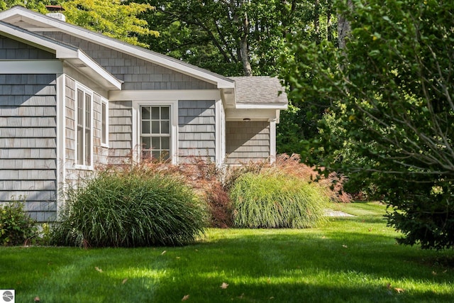 view of home's exterior featuring a shingled roof and a lawn