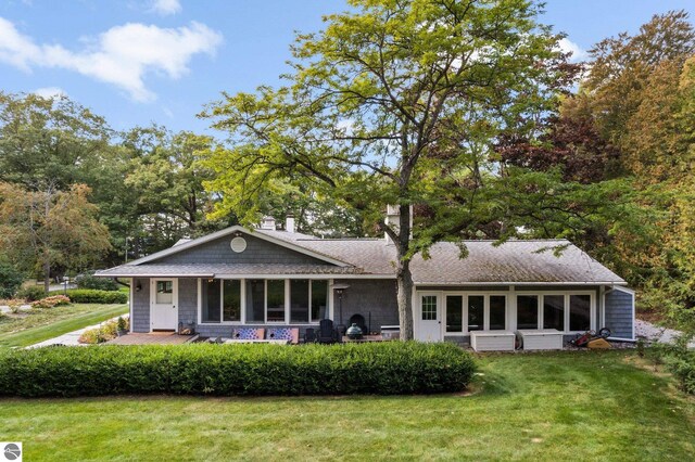 rear view of property with a lawn and a shingled roof