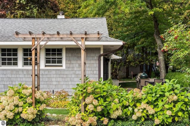 exterior space featuring roof with shingles and a chimney