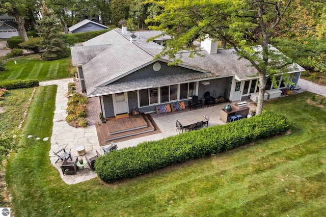 rear view of property featuring a patio area, a shingled roof, a chimney, and a lawn