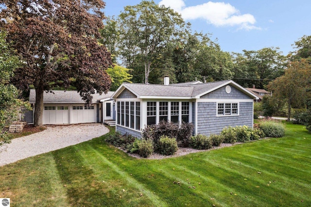 back of house featuring roof with shingles, driveway, and a lawn