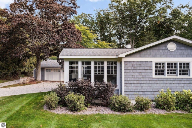 view of property exterior with a shingled roof, a yard, and driveway