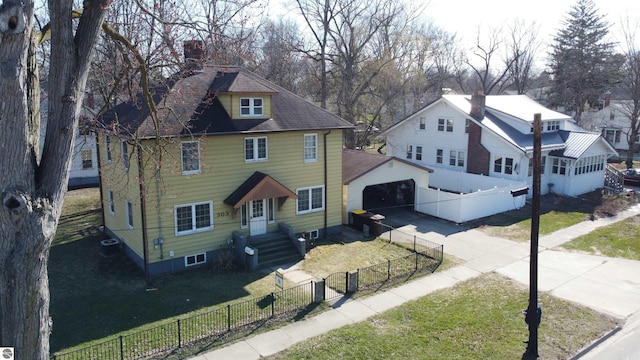 303 W Washington Ave, Saint Louis, MI 48880 - view of front of property featuring a front yard, a detached garage, a chimney, a fenced front yard, and driveway