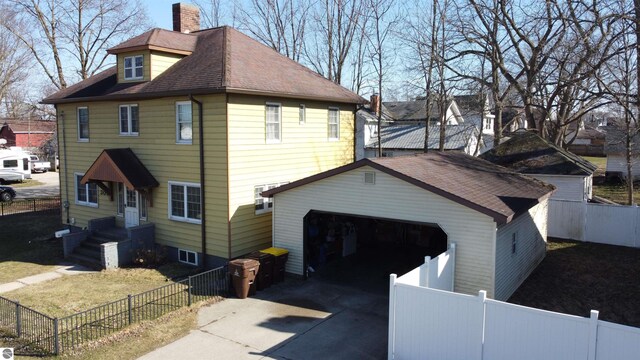303 W Washington Ave, Saint Louis, MI 48880 - view of property exterior with concrete driveway, roof with shingles, a chimney, and a fenced front yard