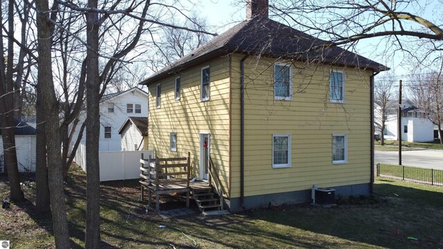 303 W Washington Ave, Saint Louis, MI 48880 - back of house with a chimney, fence, and central AC