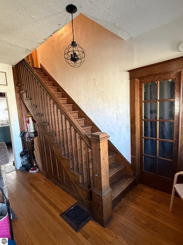 303 W Washington Ave, Saint Louis, MI 48880 - staircase with hardwood / wood-style floors and a textured ceiling