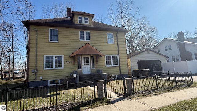 303 W Washington Ave, Saint Louis, MI 48880 - traditional style home featuring a garage, driveway, a chimney, and a fenced front yard