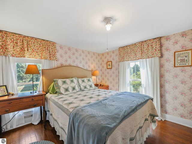 bedroom with hardwood / wood-style floors, wallpapered walls, baseboards, and multiple windows