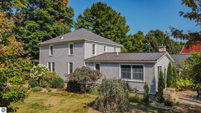 rear view of property with a yard and metal roof