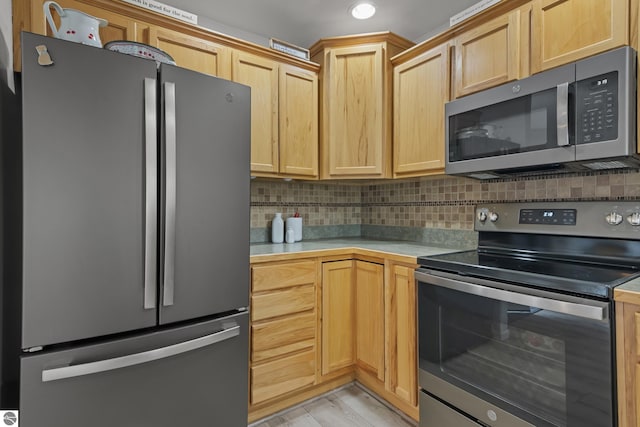 kitchen featuring recessed lighting, light countertops, backsplash, stainless steel appliances, and light brown cabinetry