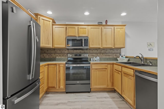 kitchen with a sink, appliances with stainless steel finishes, light brown cabinetry, and light wood finished floors