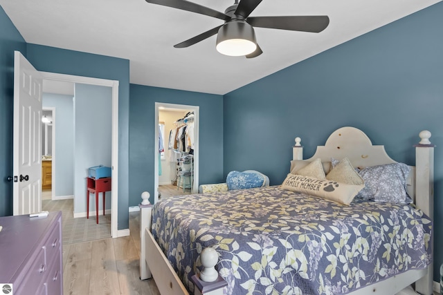 bedroom with a closet, baseboards, a spacious closet, ceiling fan, and wood finished floors