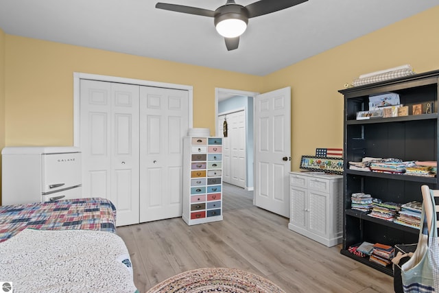 bedroom featuring a closet, light wood-style flooring, freestanding refrigerator, and ceiling fan