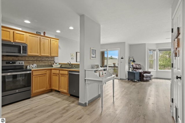 kitchen with a sink, open floor plan, light wood-type flooring, and stainless steel appliances