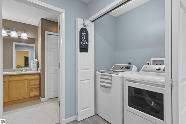 clothes washing area with baseboards, a sink, light tile patterned floors, laundry area, and washing machine and clothes dryer