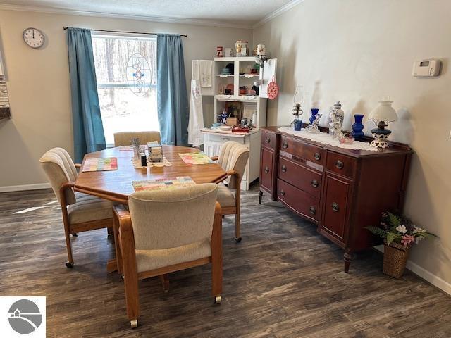 dining area with dark wood-style flooring, ornamental molding, and baseboards