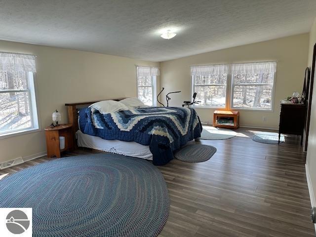 bedroom with wood finished floors, a textured ceiling, and baseboards