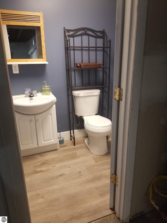bathroom featuring baseboards, wood finished floors, toilet, and vanity