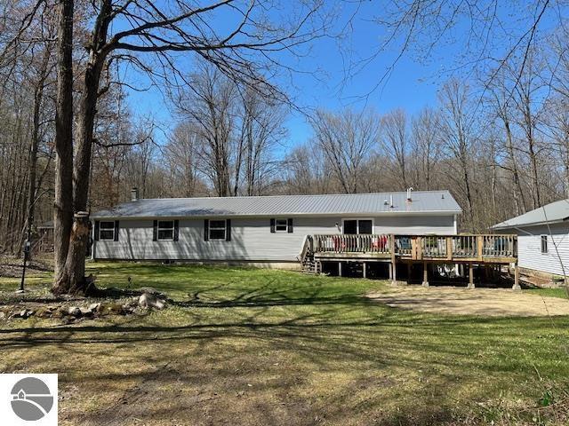 4607 Del Mason Rd, Bellaire, MI 49615 - back of property with metal roof, a wooden deck, and a lawn