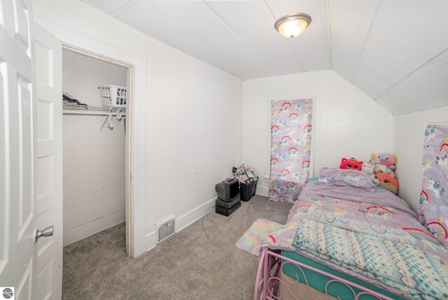 carpeted bedroom with visible vents, a closet, and vaulted ceiling