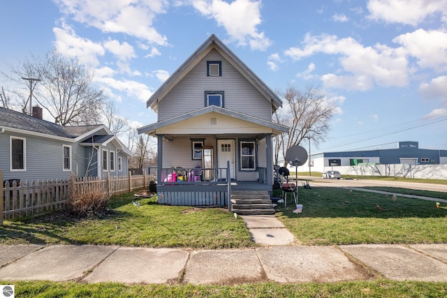 view of front of property featuring a porch, fence, and a front lawn
