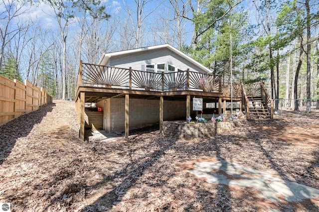 rear view of property featuring fence, stairway, and a wooden deck