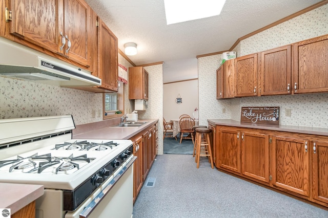 kitchen with a sink, wallpapered walls, ornamental molding, and white gas range