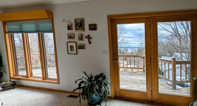 entryway featuring visible vents, light colored carpet, and baseboards