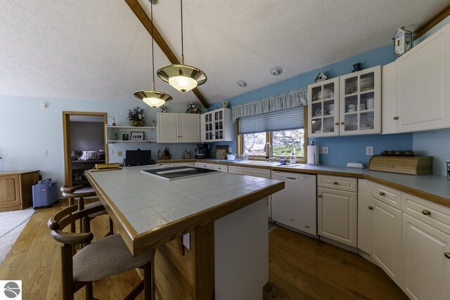 kitchen with tile countertops, lofted ceiling with beams, a textured ceiling, dishwasher, and dark wood-style flooring