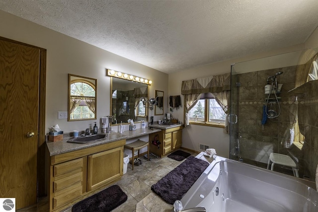 bathroom with vanity, baseboards, a stall shower, a textured ceiling, and visible vents