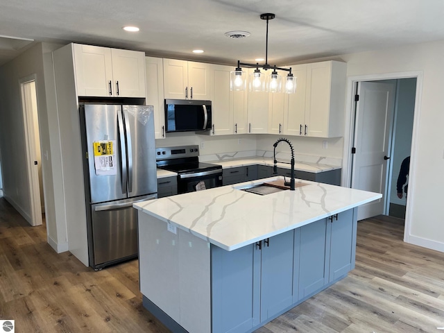 kitchen featuring light stone counters, light wood-style flooring, stainless steel appliances, and a sink