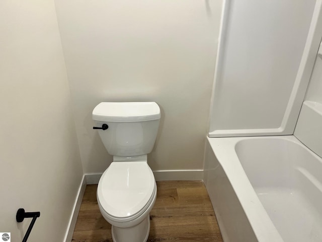 full bathroom featuring baseboards, toilet, a tub to relax in, and wood finished floors