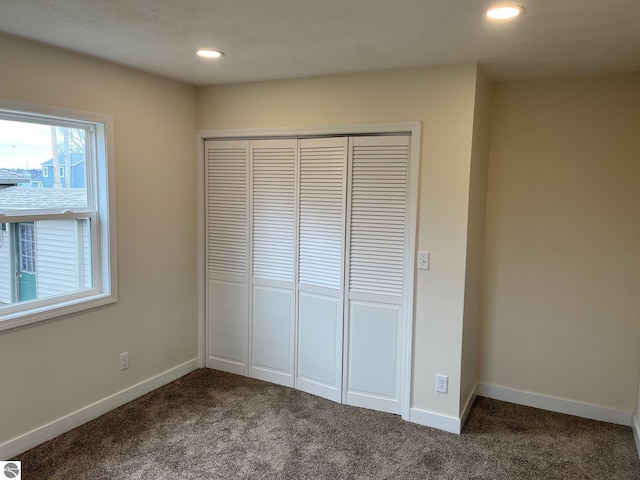 unfurnished bedroom featuring baseboards, recessed lighting, carpet flooring, and a closet