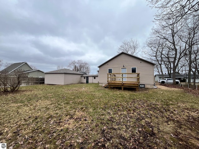 rear view of property with a wooden deck, fence, and a yard