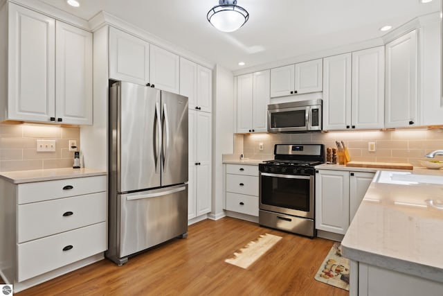 kitchen with tasteful backsplash, white cabinets, recessed lighting, appliances with stainless steel finishes, and a sink