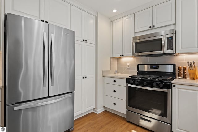 kitchen featuring white cabinetry, recessed lighting, appliances with stainless steel finishes, light countertops, and light wood finished floors