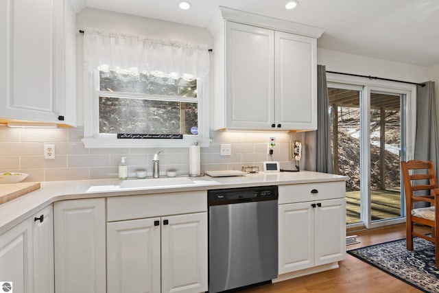 kitchen with light wood-type flooring, white cabinets, decorative backsplash, dishwasher, and a sink