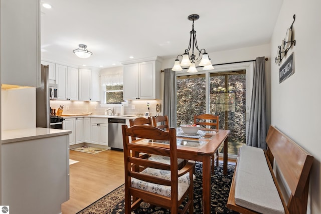 dining area with light wood finished floors, a notable chandelier, and recessed lighting