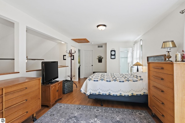 bedroom featuring visible vents, attic access, and wood finished floors