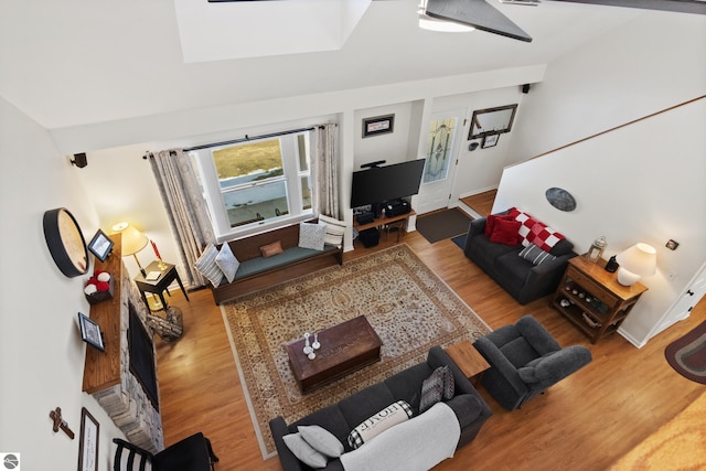 living area featuring a skylight, wood finished floors, and baseboards