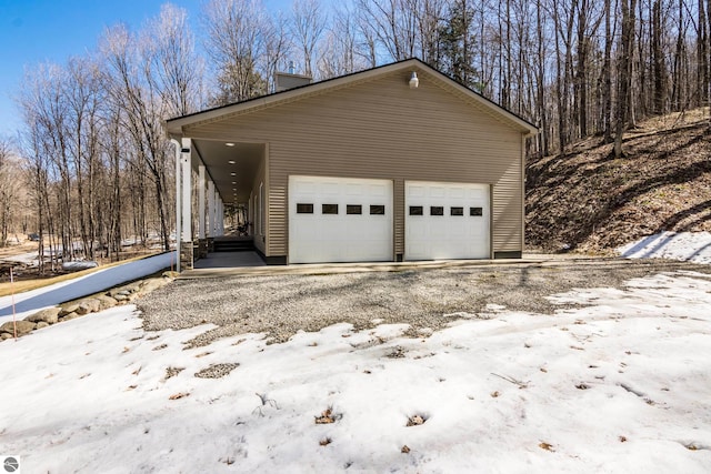 view of snowy exterior with a detached garage