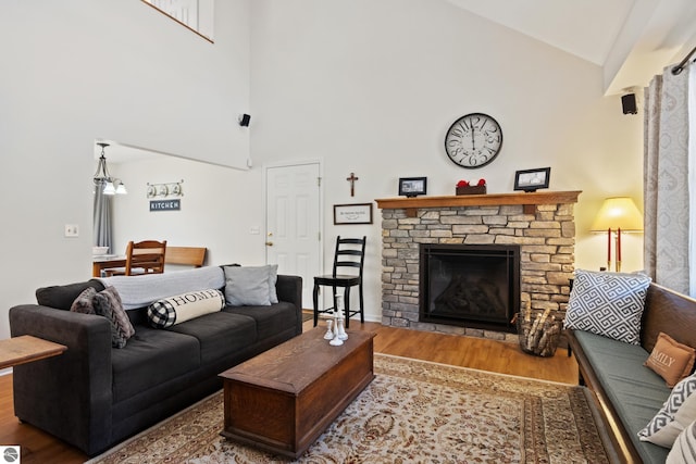 living room with wood finished floors, high vaulted ceiling, and a stone fireplace