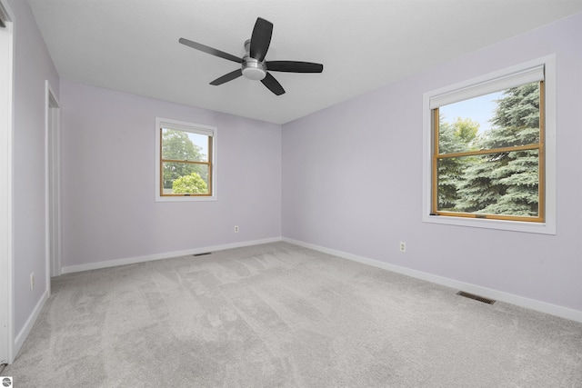 empty room featuring light carpet, visible vents, baseboards, and a ceiling fan