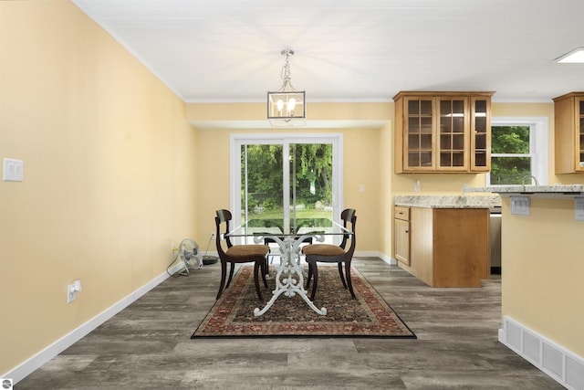dining space featuring dark wood-type flooring, visible vents, a wealth of natural light, and an inviting chandelier