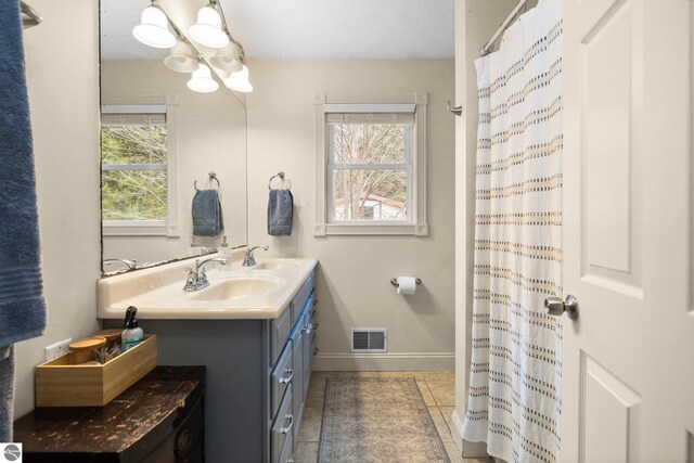 full bathroom with baseboards, double vanity, a chandelier, visible vents, and a sink