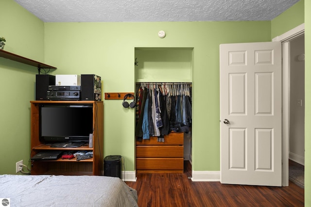 bedroom featuring a textured ceiling, wood finished floors, a closet, and baseboards