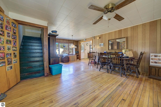 dining room featuring ceiling fan, wood-type flooring, and wooden walls